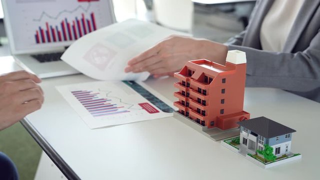 Real estate developer planning property project with building models, charts, and investment analysis.